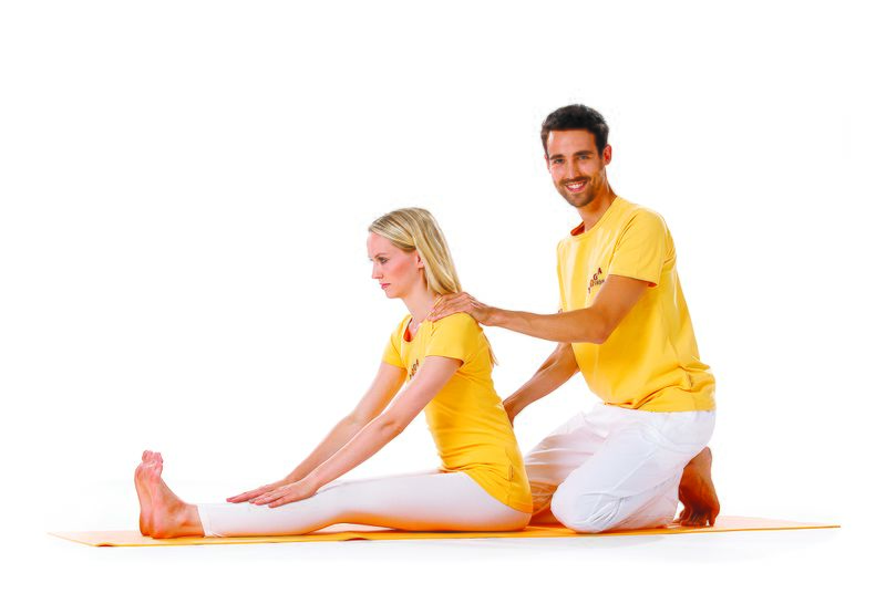 Datei:Unterrichten Yogalehrer Hilfestellung Asana Vorwärtsbeuge.jpg