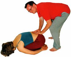 3) Weitere Hilfe zum Entspannen: Sanft mit beiden Händen gegen das Kreuzbein bzw. gegen die Beckenknochen drücken.
