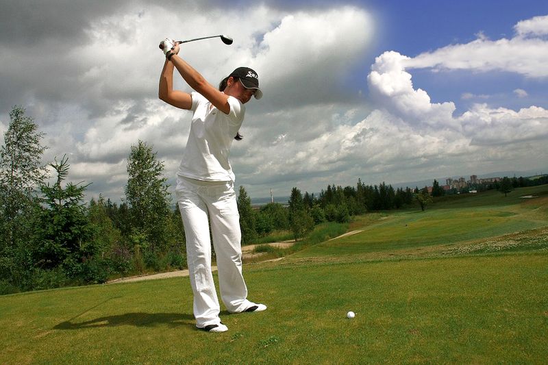 Datei:Golf spielen Golfspieler Frau weiß Rasen Wolken.jpg