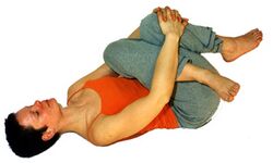 Kreuzstreckung: Beide Knie beugen ein Knie über das andere. Mit beiden Händen um das Knie fassen, das weiter weg ist. Das Knie zur Brust ziehen. 5-8 Atemzüge lang halten. Seite wechseln.