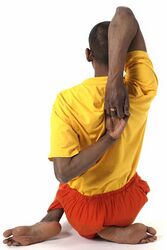 (14) Virasana, eine machtvolle Energie-Übung: Du sitzt auf einer Ferse. Das andere Bein wird über den Oberschenkel geschlagen. Die Finger hinter dem Rücken verhaken.