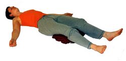 9. Tiefenentspannung: 5-15 Minuten lang auf dem Rücken liegen. Bei Rückenbeschwerden gerollte Decke unter Knie oder Oberschenkel legen. Beine auseinander, Füße locker nach außen fallen lassen. Arme vom Körper weg, Handflächen nach oben. Tiefenentspannungstechnik anwenden.