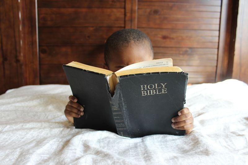 Datei:Kind Bibel Bett heilige Schrift Schriften Buch.jpg