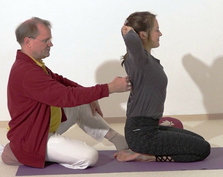 Datei:Im Kniesitz in die Rueckwaertsbeuge helfen - Yoga Vidya Bodywork 1.jpg